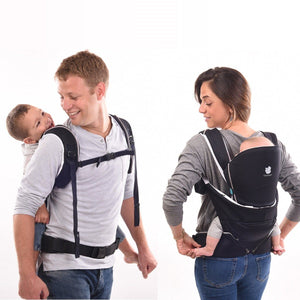 mom back carrying her baby and dad back carrying his toddler, both in the Cococho baby carrier