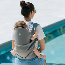Load image into Gallery viewer, Mom is seating by the pool, carrying her baby on her back in the Cococho Baby Carrier Grey model