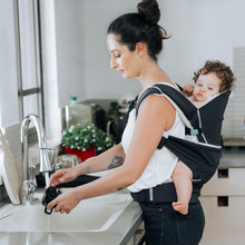 Load image into Gallery viewer, A mom is back carrying her baby girl in the Cococho Baby Carrier and washing the dishes 