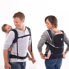 Load image into Gallery viewer, mom back carrying her baby and dad back carrying his toddler, both in the Cococho baby carrier