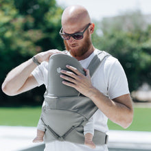 Load image into Gallery viewer, A bold dad with beard and sun glasses wears the Cococho Ergonomic Baby Carrier in the front position
