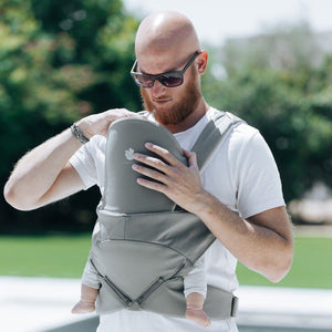 A bold dad with beard and sun glasses wears the Cococho Ergonomic Baby Carrier in the front position
